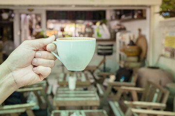 Front view of young man holding hot coffee cup the best start to any morning at the cafe. 