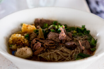 Asian noodles with cooked beef in traditional ceramic bowl. Thai peoples call Boat Noodles.