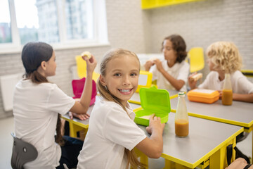 Schoolchildren having lunch in the classrom and looking excited