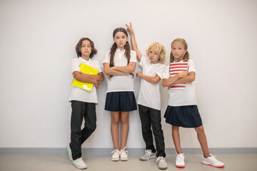 Fototapeta premium Schoolchildren standing near the wall and feeling as a team