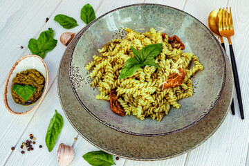  Italian pasta with pesto sauce and sun-dried tomatoes on a white wooden table