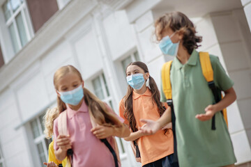 Schoolchildren in protective masks having conflict in the school yard