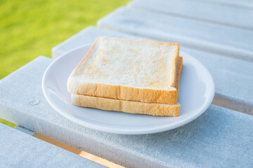 Toast bread in white plate on wooden table in the cafe.
