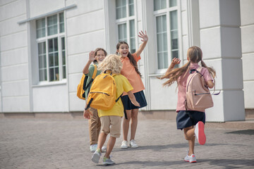 Schoolchildren meeting after lessons in school yard and feeling good