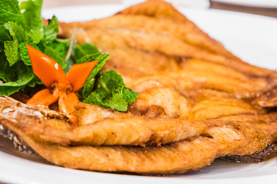 Deep fried Snapper topped with fish sauce in white dish serving on table. Pla kapong tod num pla. Popular traditional Thai style food.