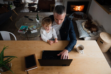 Fototapeta na wymiar Father and daughter bonding playing videos on laptop sitting in lounge