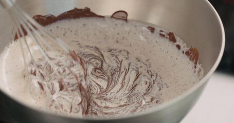 whisking cream with chocolarte in steel bowl