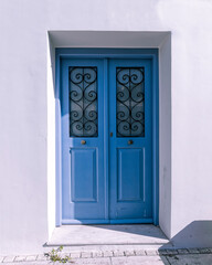 simple double blue painted wooden door and white washed wall, Athens Greece