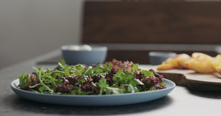 making salad with nectarines and mozzarella on a blue plate on concrete countertop on kitchen