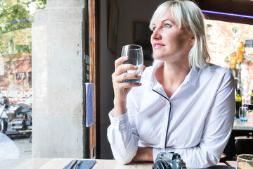 Young blonde woman drinking coffee in cafe