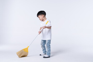 Asian boy doing chore by sweep the house floor with plastic broom