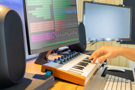 male songwriter hand playing keyboard for recording midi track on computer. music production concept