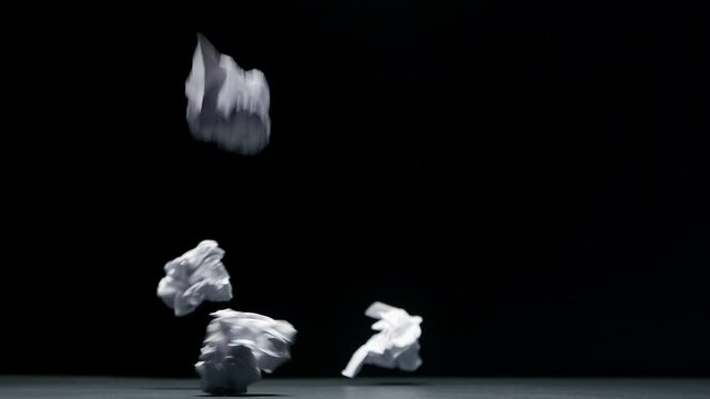 Crumpled paper falls on a black background in slow motion
