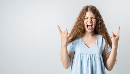 Image of excited woman making horn gesture with fingers. Emotions and body language. Studio shot white background