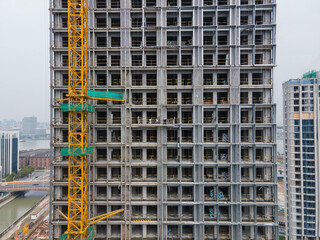 Fototapeta na wymiar Aerial view moving around the building in construction. Real estate development concept. Crane tower and elevator in the construction site. Worker working in the window clean lift. Office or apartment