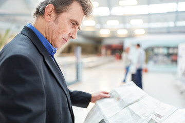 Business Mann liest Tageszeitung im Flughafen
