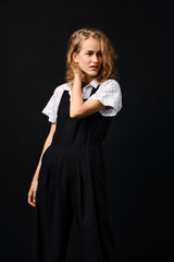 Fototapeta premium Young fashion model in black pantsuit and white shirt posing over black background