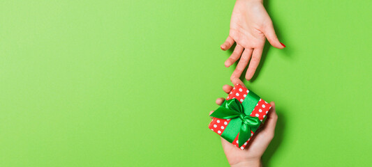 Top view of a man and a woman holding a gift box on colorful background. Love and relationship concept. Copy space
