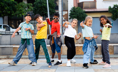 Smiling girls and boys hip hop dancers doing dance workout during open air group class