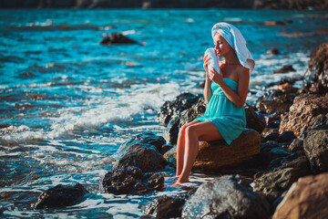 Attractive woman sit on rock near crystal clean sea. Sea spa, relax and beauty day. Relaxation and summer time concept