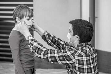 Dad with a son in a medical mask. Father puts a medical mask on her son. Coronavirus, illness, infection, quarantine, medical mask. Black and white