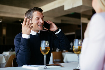 Handsome businessman dressed in the suit drinking wine. Businessman enjoying in the restaurant.