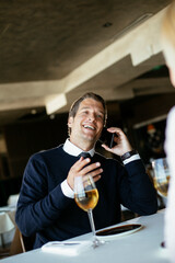 Handsome businessman dressed in the suit drinking wine. Businessman enjoying in the restaurant.