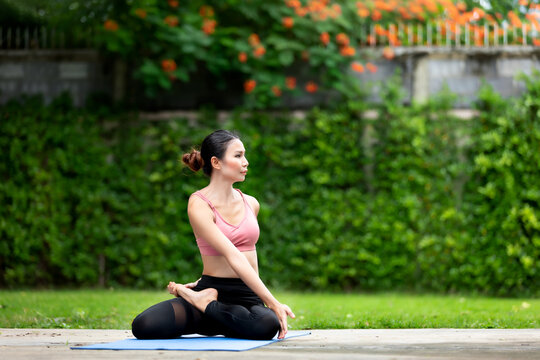 Image of amazing strong young Asia fitness woman outdoors in the garden make yoga stretching exercises.