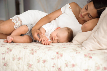 Obraz na płótnie Canvas Little boy lies near his mom resting on the bed.