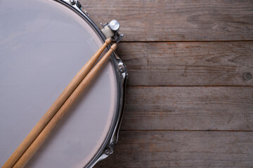 Drum stick and drum on wooden table background, top view, music concept