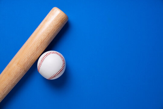 baseball and baseball bat on blue table background, close up