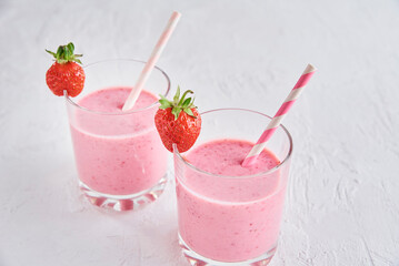 Strawberry milk shake in glass with straw and fresh berries on a white background