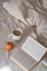 Morning. Cup of coffee, peach and book on the bed. Lifestyle. Mentlhealth. The consept of heathy life.