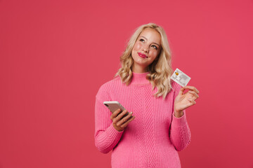 Image of pleased beautiful woman holding mobile phone and credit card