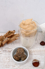 Dry fruit balls in the white bowl with chestnut on the wood background. Homemade candy with dalgona coffee