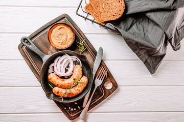 Fried sausages with bread and mustard in a frying pan, top view, copyspace