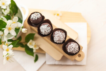 Sweet chocolate balls with coconut lie on a colored white background. In the style of boho and rustic