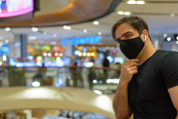 Portrait of Persian man with mask thinking at the mall in the city indoors
