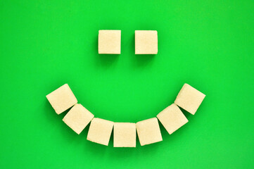 Cheerful emoticon from refined sugar on a green background.