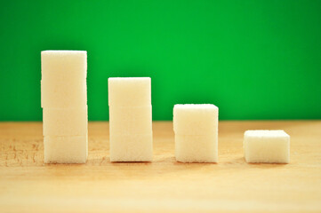 Refined sugar lies in descending order on a wooden background. Against the background of a green...