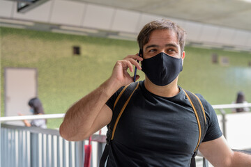 Portrait of Persian man with mask talking on the phone at the sky train station
