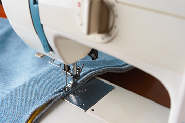 sewing machine. the process of sewing a decorative cord of blue fabric.