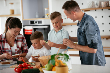 Mother and father making breakfast with sons. Young family preparing delicious food in kitchen.