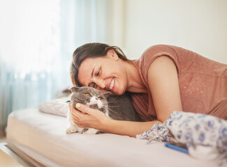 Happy woman in the bedroom hugs her cat.