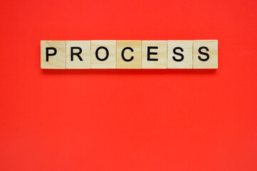 Word process. Wooden blocks with lettering on top of red background. Top view of wooden blocks with letters on red surface