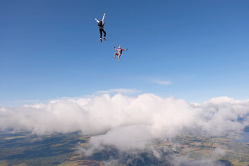 Fototapeta na wymiar Skydiving. Two skydivers are flying and having fun above white clouds.