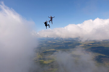Fototapeta na wymiar Skydiving. Two skydivers are flying and having fun above white clouds.