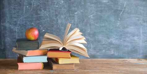 books in front of school black board and red apple.Back to school, education, learning concept, free copy space