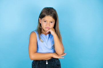 Young beautiful child girl over isolated blue background thinking looking tired and bored with crossed arms