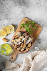 Boiled clams in a wooden bowl on a light gray table. Shellfish close-up. Seafood dish. Top view with space for text